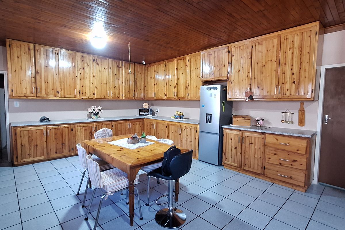 Spacious kitchen featuring extensive wooden cabinetry, tiled flooring, and a wood-paneled ceiling, providing a traditional farm-style aesthetic with ample storage and workspace.