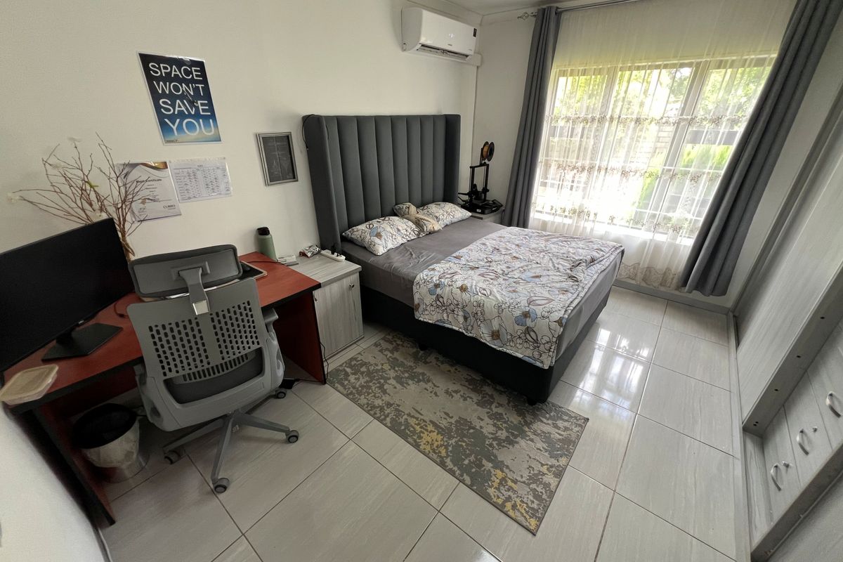 A well-maintained bedroom featuring tiled flooring, a built-in wardrobe, and a wall-mounted split-system air conditioner for climate control.