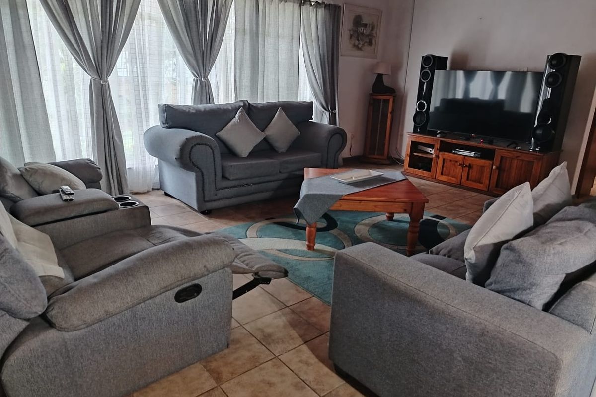 A comfortable living room featuring tiled flooring and large windows with curtains, providing a bright and functional space for relaxation.