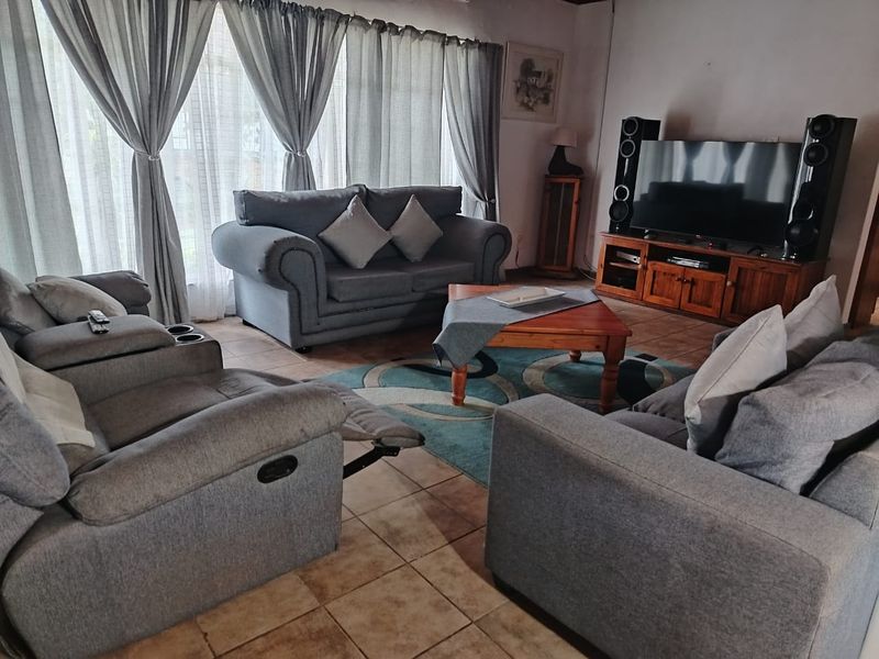 A comfortable living room featuring tiled flooring and large windows with curtains, providing a bright and functional space for relaxation.
