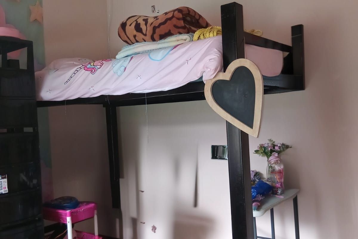 A bedroom featuring parquet flooring and neutral wall finishes, currently utilized as a child's sleeping area.