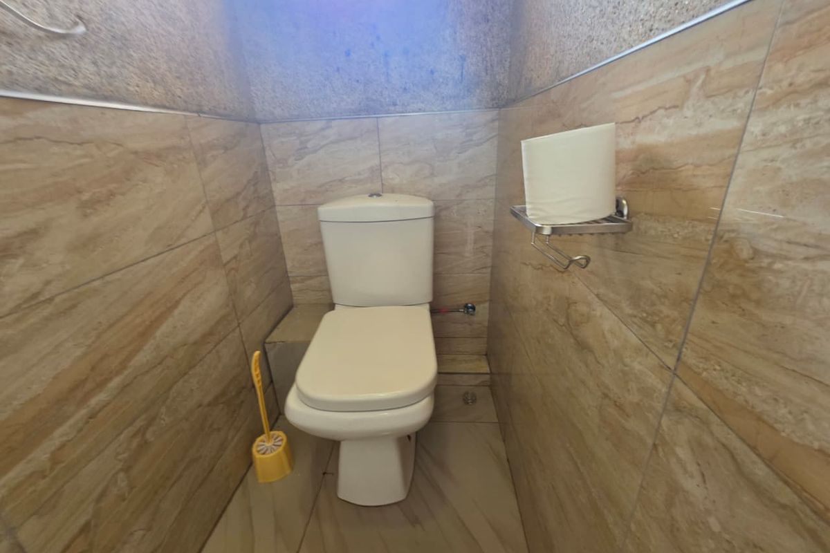 A compact bathroom featuring full-height wall tiling and a standard ceramic toilet suite.