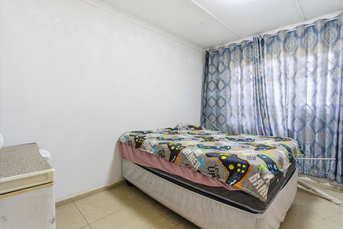 A standard bedroom featuring tiled flooring and a window with curtain tracks.