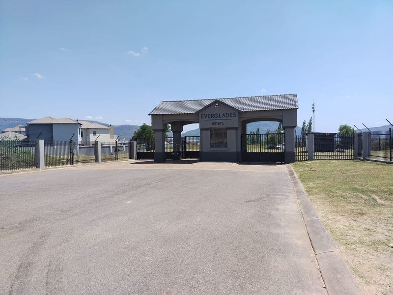 The main entrance gatehouse of Everglades Estate, featuring a tiled roof structure, security access point, and perimeter fencing.