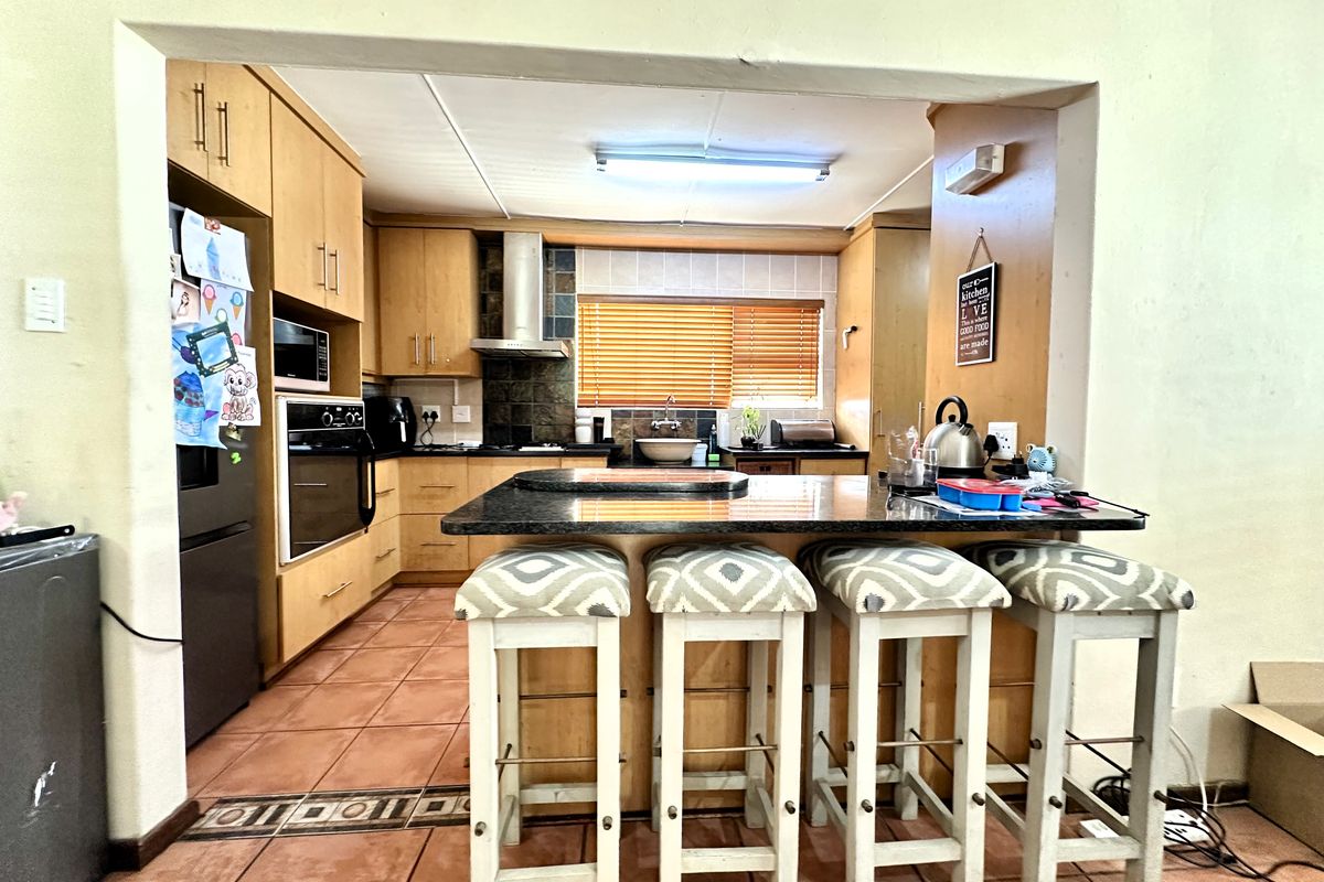 A functional kitchen featuring light wood cabinetry, granite countertops, a breakfast bar, and tiled flooring, providing a practical space for cooking and casual dining.