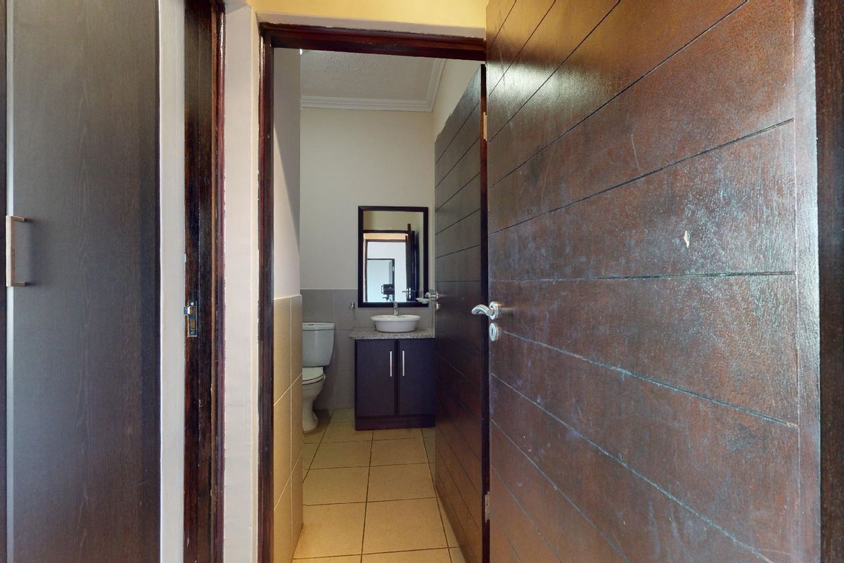 A view through a doorway into a functional bathroom featuring a vanity cabinet with a vessel sink and a standard toilet.