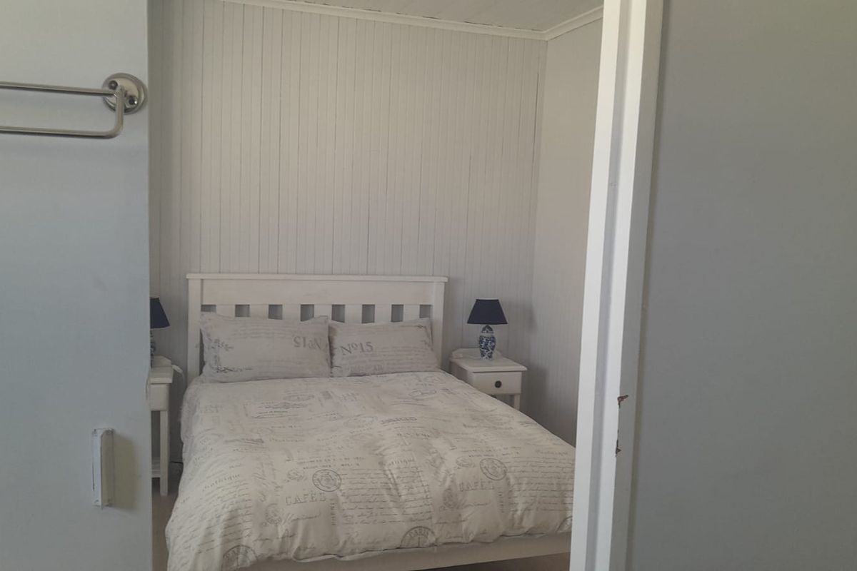 A cozy bedroom featuring white tongue and groove wall paneling and a neutral color palette.