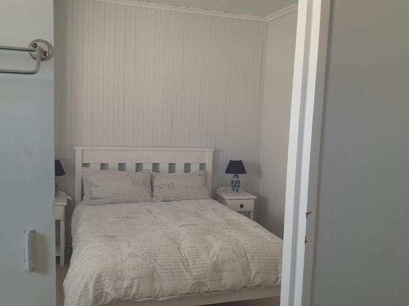 A cozy bedroom featuring white tongue and groove wall paneling and a neutral color palette.