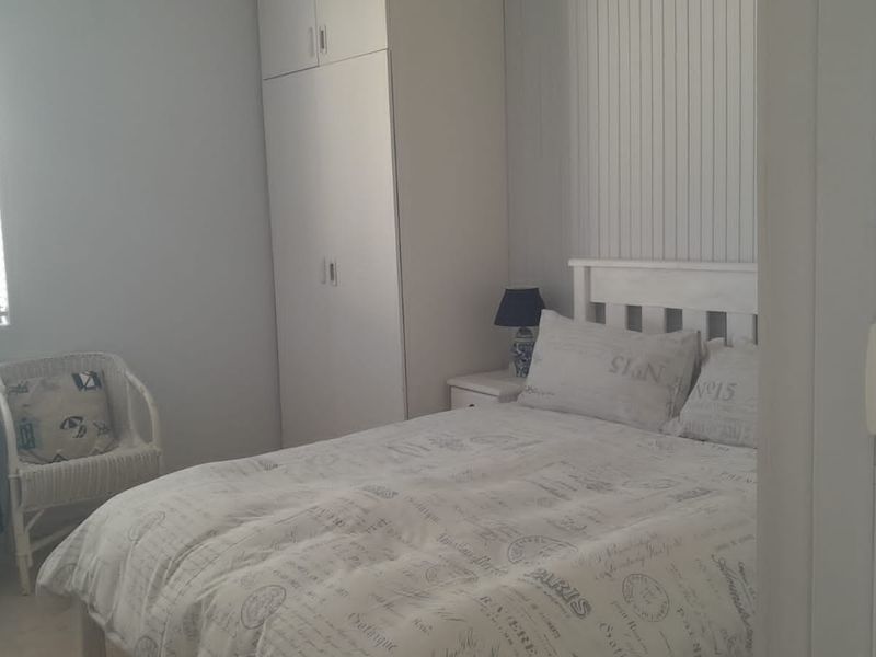 A bedroom featuring a built-in wardrobe and vertical wall paneling, providing a functional and neutral sleeping space.