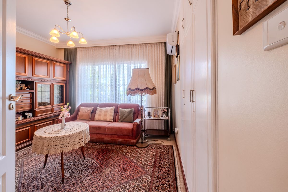 A cozy living room featuring built-in cabinetry, a split-system air conditioner, and classic cornice detailing, offering a functional and well-maintained space.