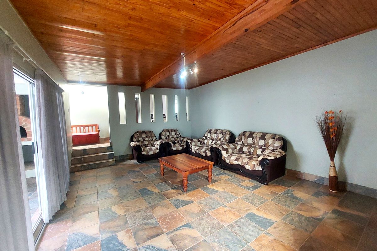 Spacious living area featuring a warm timber-clad ceiling, durable slate tile flooring, and a sliding glass door providing access to the outdoor space.