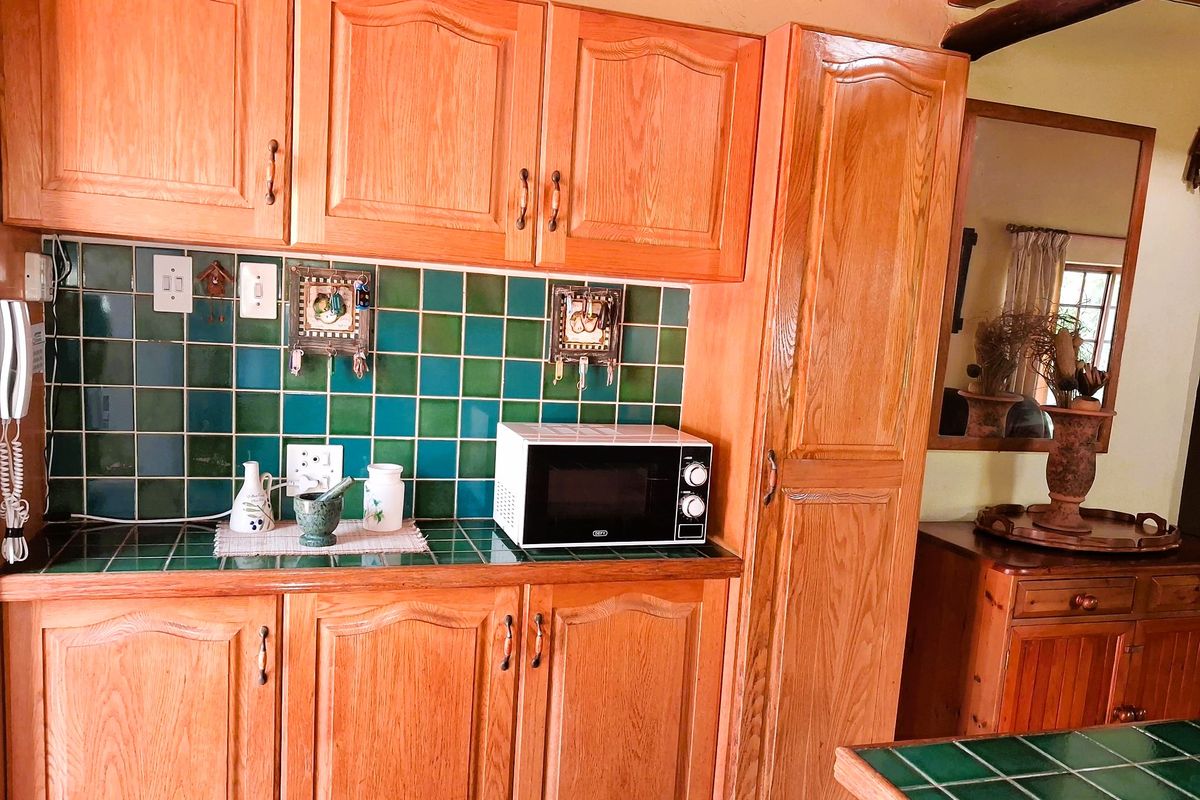A kitchen area featuring traditional wooden cabinetry, a green tiled backsplash, and a matching tiled countertop with built-in storage.