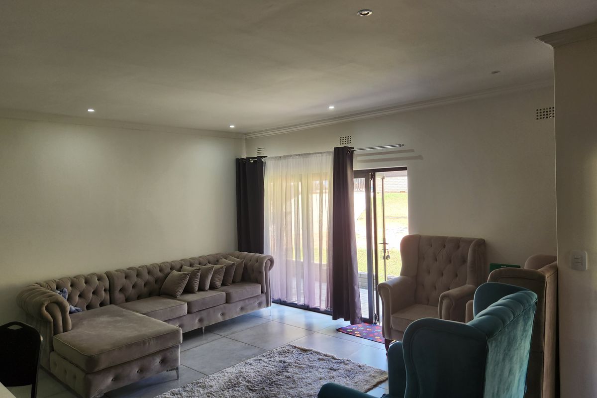 A spacious living room featuring tiled flooring, recessed downlighting, and a sliding glass door providing direct access to the outdoor area.