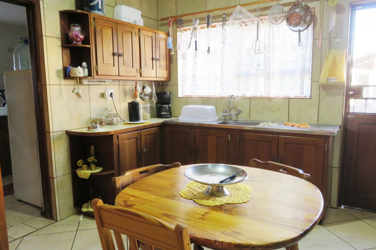A dated kitchen featuring wooden cabinetry, tiled backsplash, and tiled flooring, offering a functional layout with potential for modern renovation.