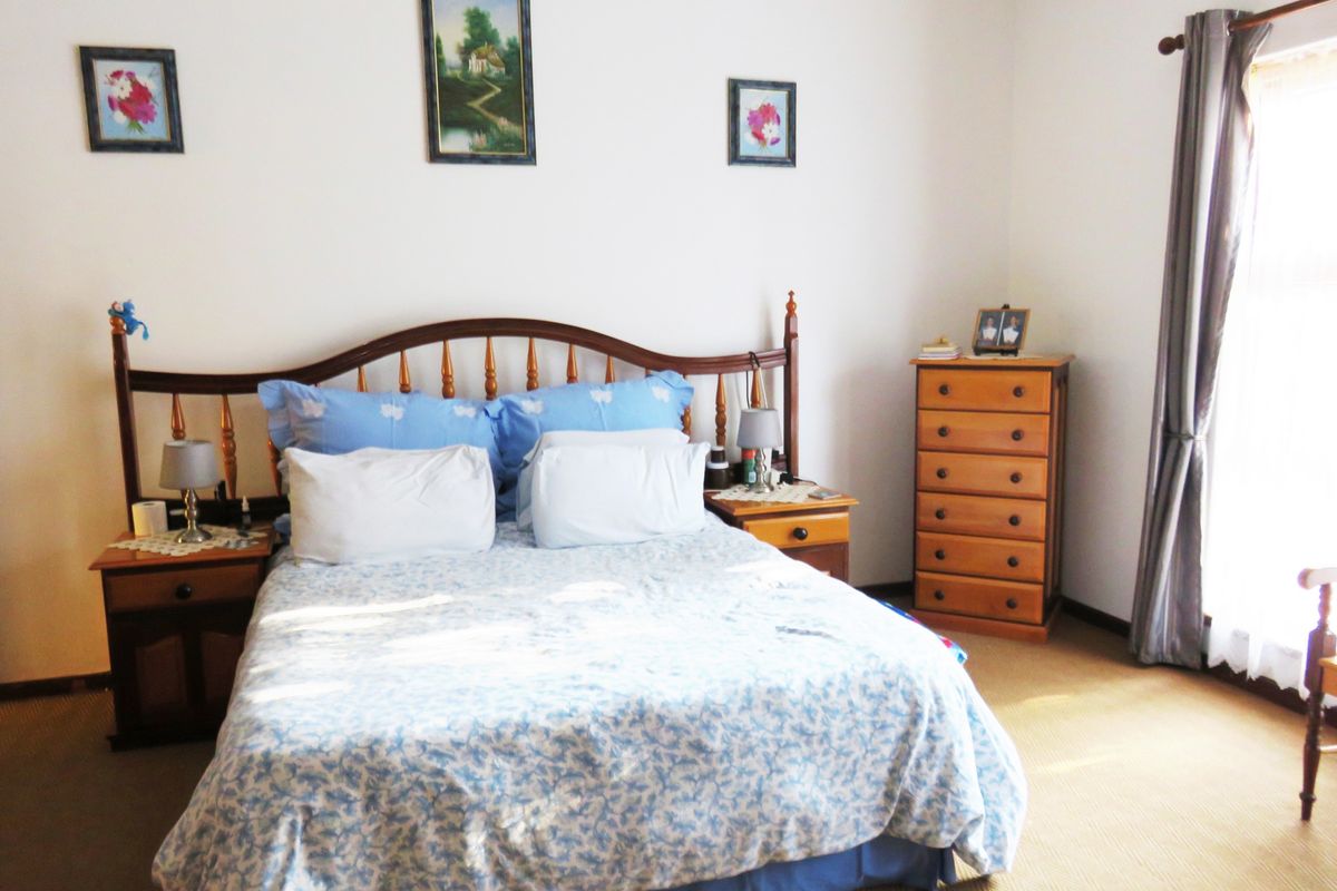 A standard bedroom featuring carpeted flooring and a window with installed curtain rods.