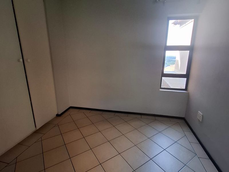 An empty bedroom featuring tiled flooring and built-in cupboards, offering a clean and neutral space ready for personalization.