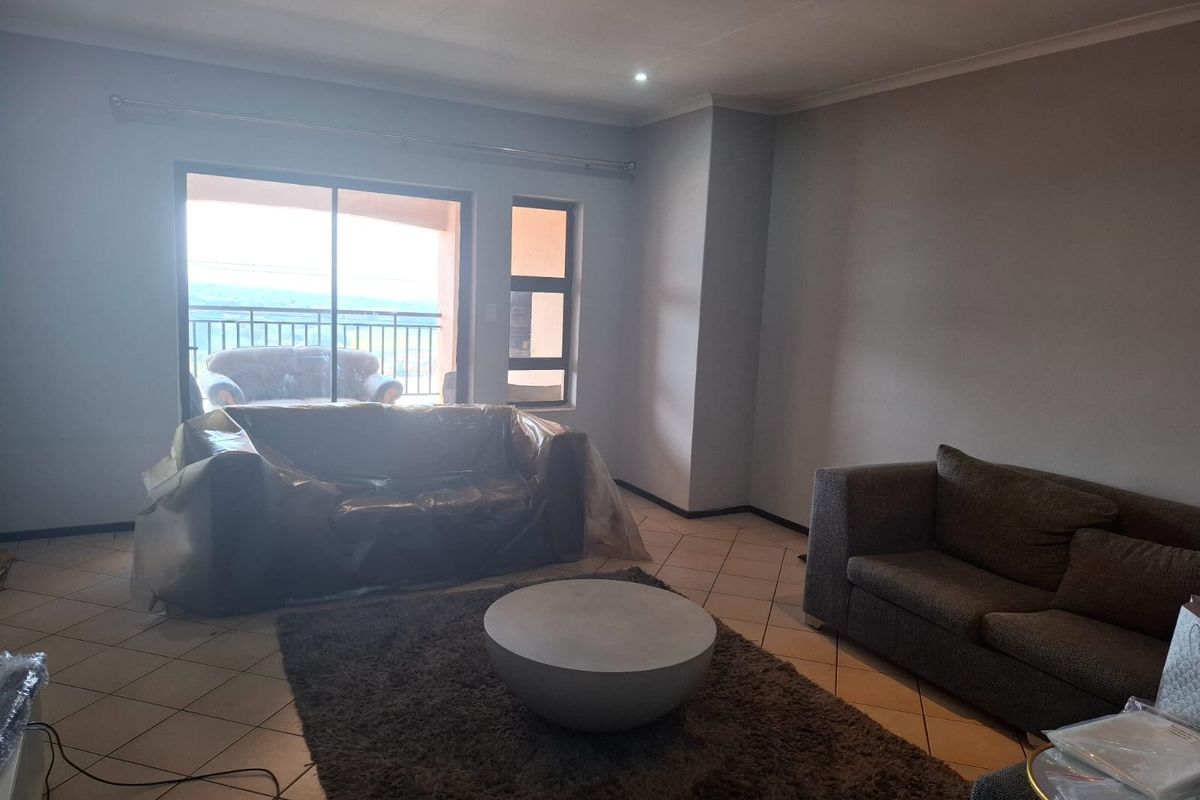 A spacious living room featuring tiled flooring, recessed lighting, and a sliding glass door providing access to an outdoor balcony area.