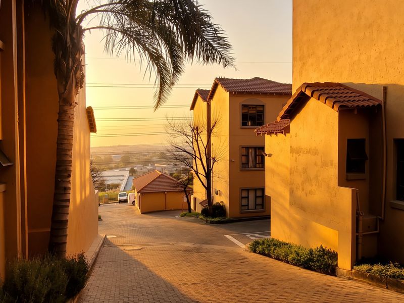 View of the apartment complex driveway and exterior facades during sunset, featuring paved surfaces and multi-story residential buildings.