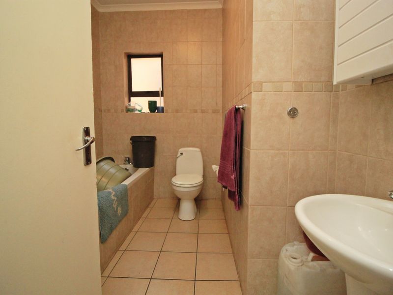 A functional bathroom featuring tiled walls and flooring, equipped with a bathtub, toilet, and pedestal basin.