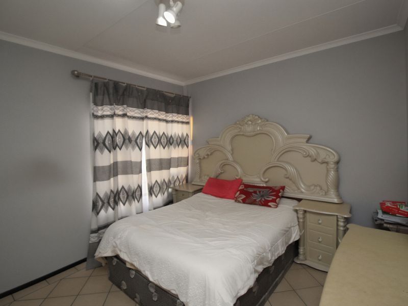 A bedroom featuring tiled flooring and neutral wall finishes, providing a functional space with natural light access through the window.