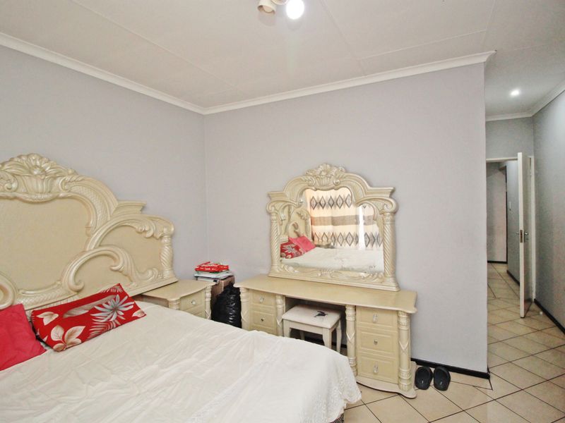 A bedroom featuring tiled flooring and neutral wall finishes, providing a functional space with access to an adjoining hallway.