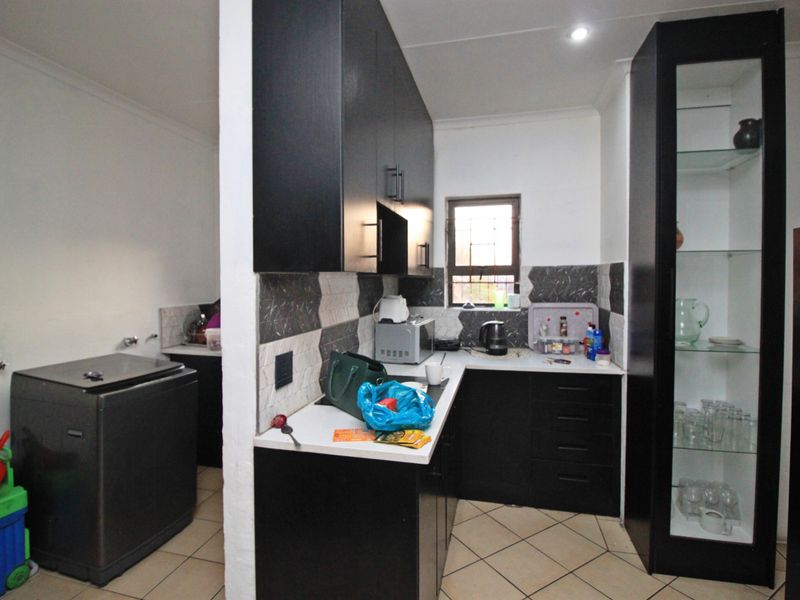 A functional kitchen featuring dark cabinetry, tiled backsplash, and a dedicated laundry area with plumbing connections, offering a practical layout for daily use.