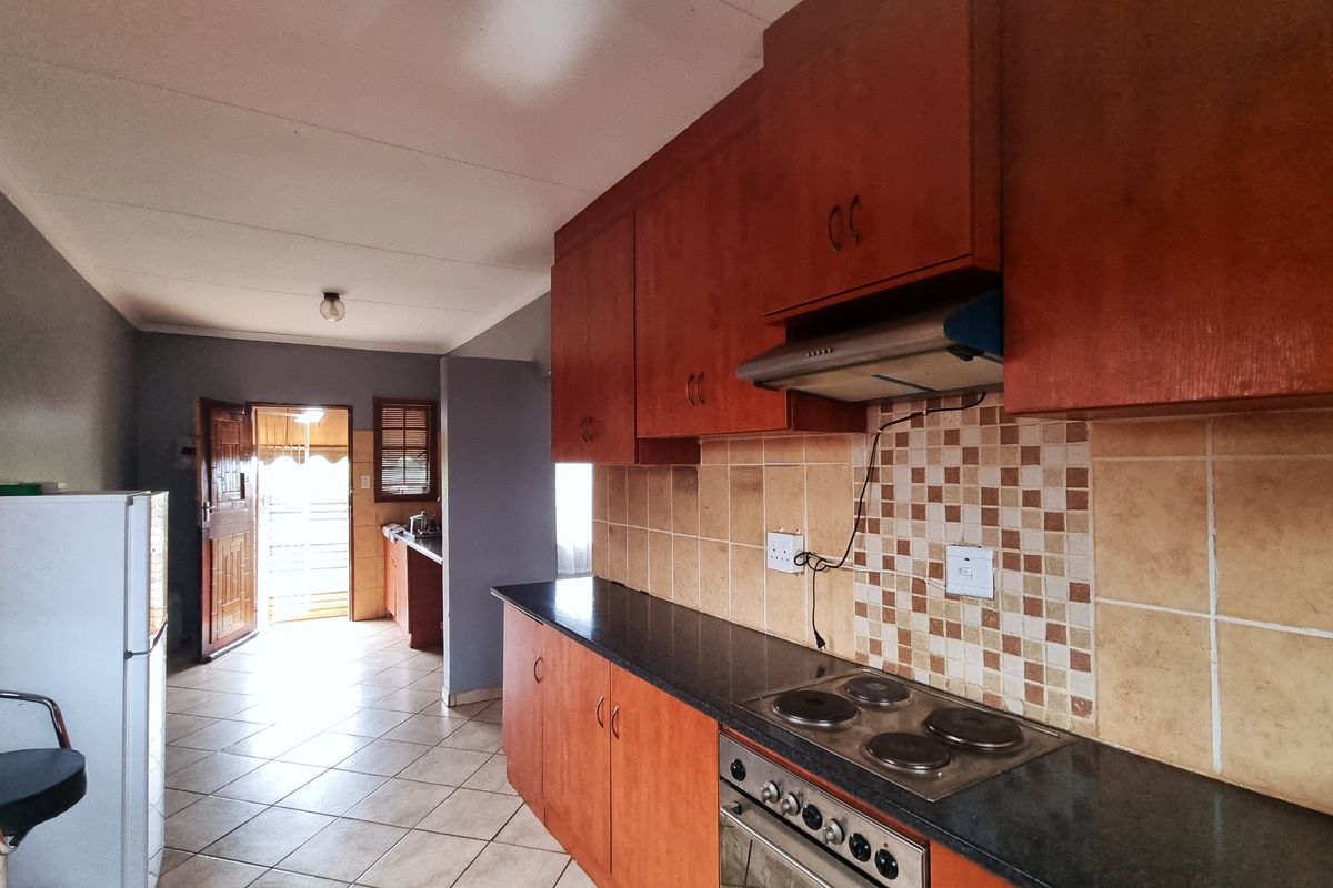 Functional kitchen featuring wooden cabinetry, built-in oven and hob, tiled backsplash, and direct access to the exterior entrance.
