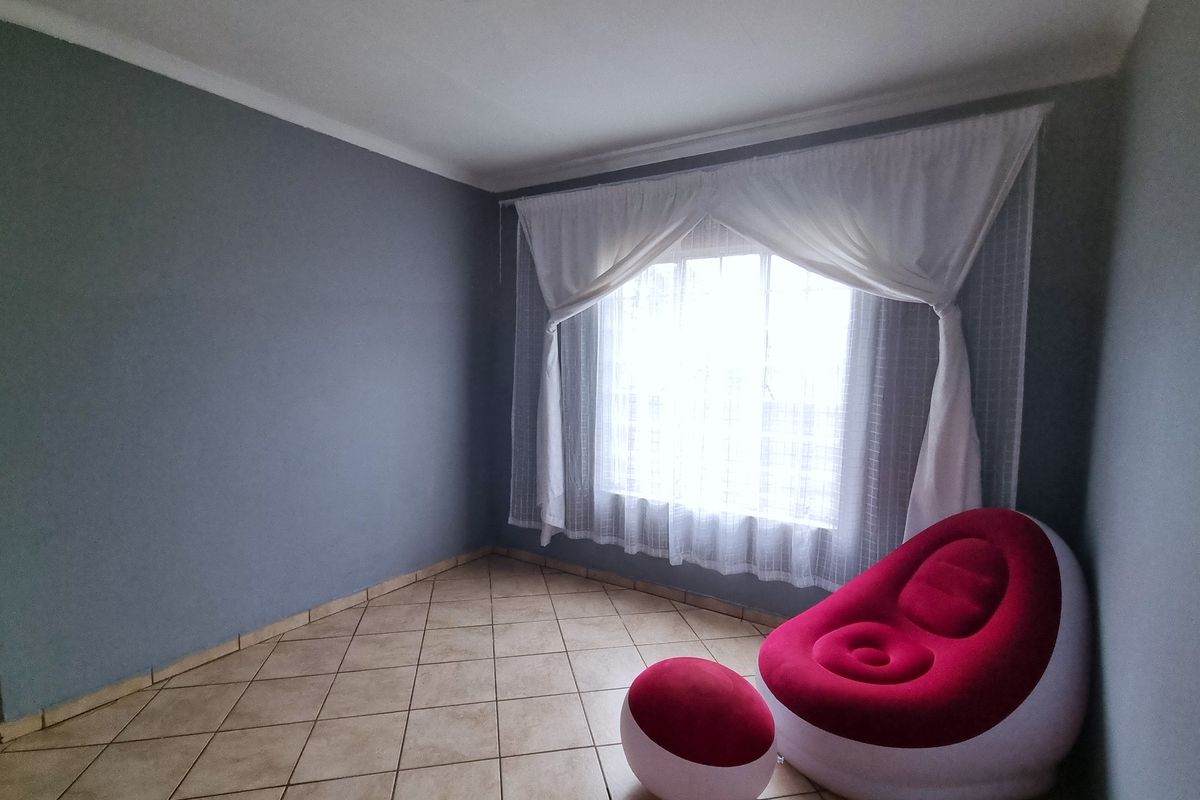 A neutrally painted bedroom featuring tiled flooring and a large window with installed curtain tracks, offering a blank canvas for personalization.