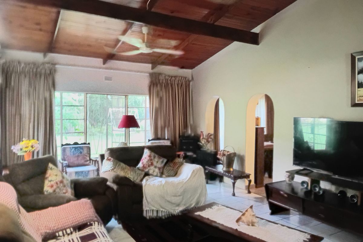 Spacious living room featuring a vaulted timber ceiling with exposed beams, ceiling fan, tiled flooring, and distinctive arched doorways leading to adjacent rooms.
