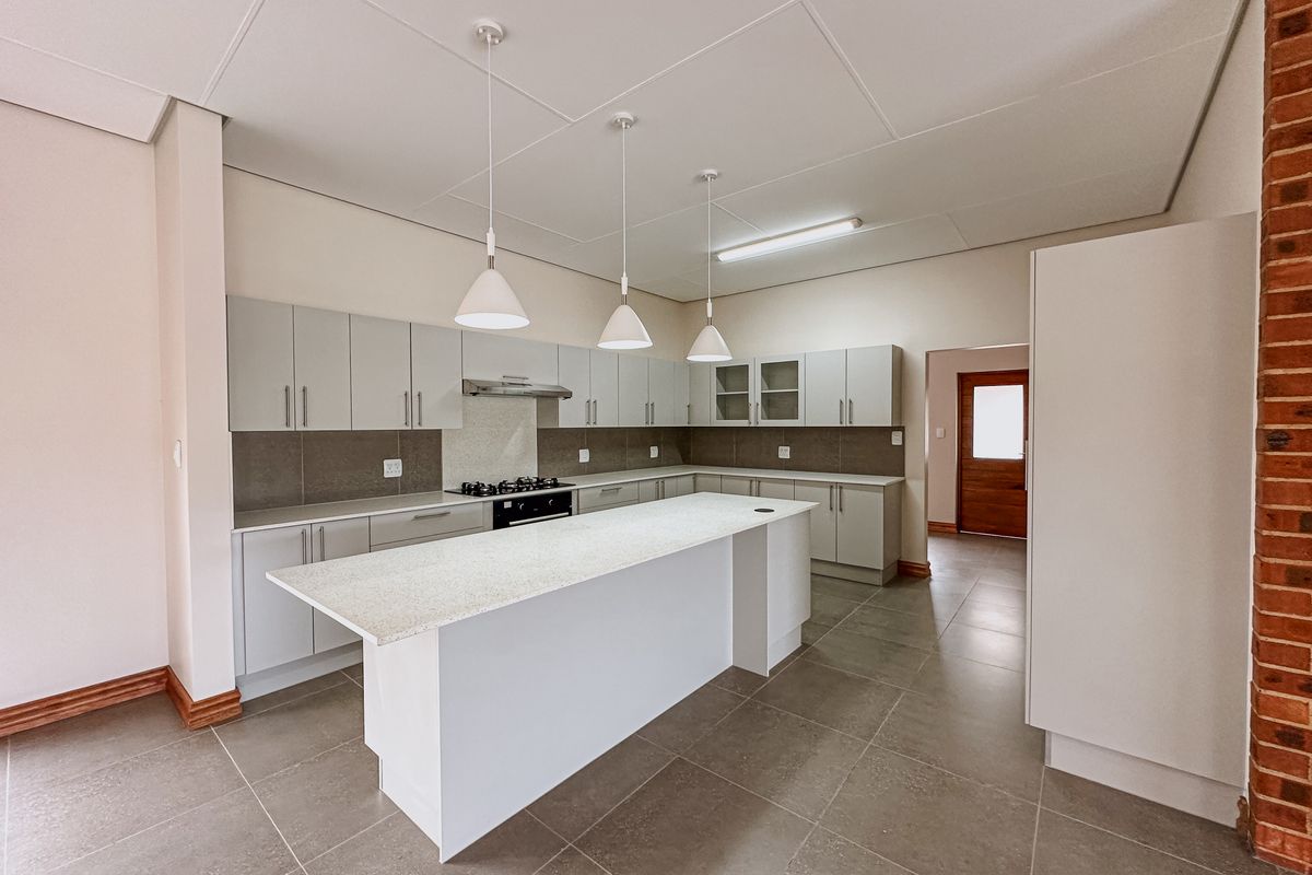 Modern kitchen featuring a central island, ample built-in cabinetry, stone countertops, gas hob, and tiled flooring in a clean, open-plan layout.