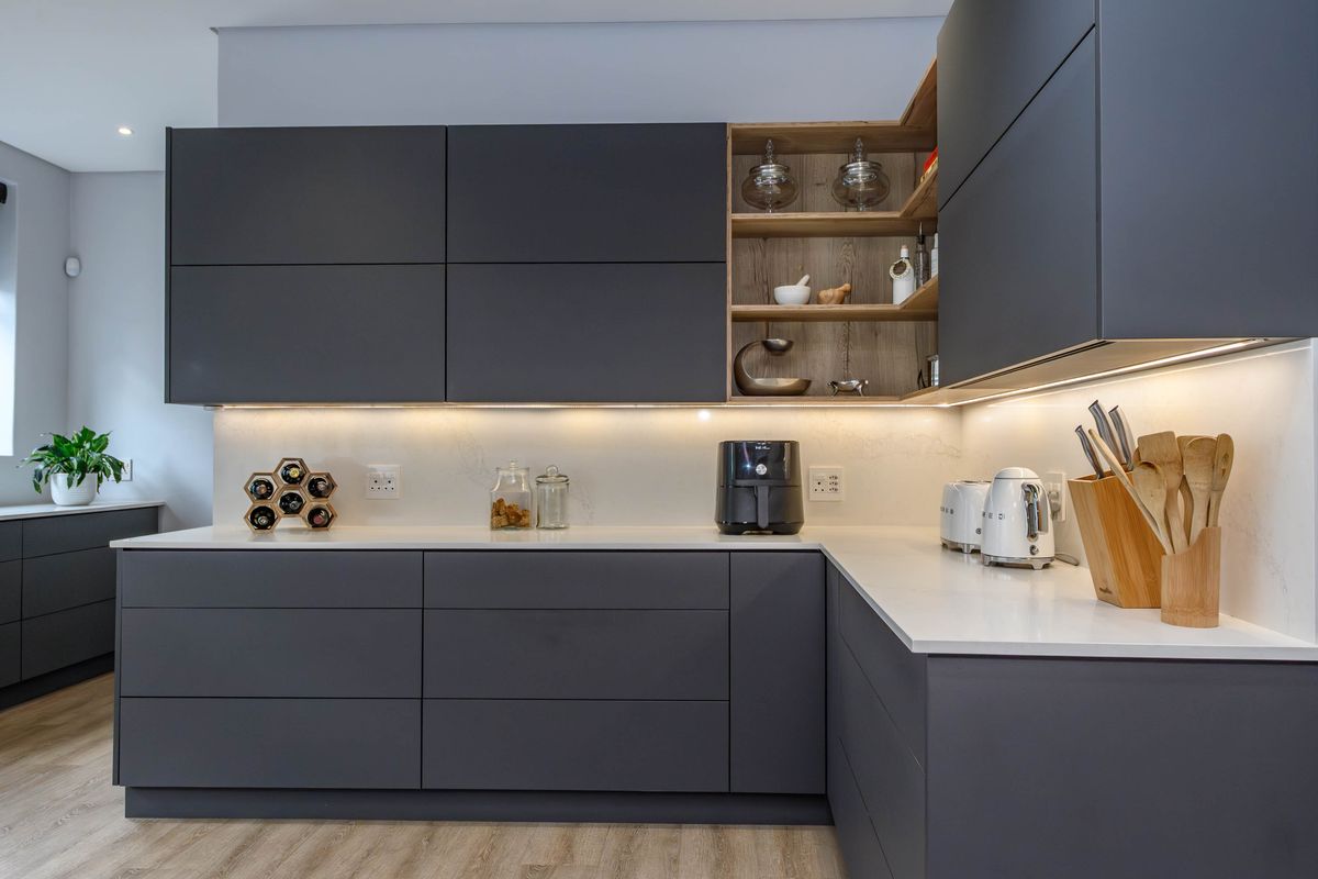 Modern kitchen featuring sleek matte charcoal cabinetry, contrasting timber open shelving, and premium quartz countertops with integrated under-cabinet lighting.