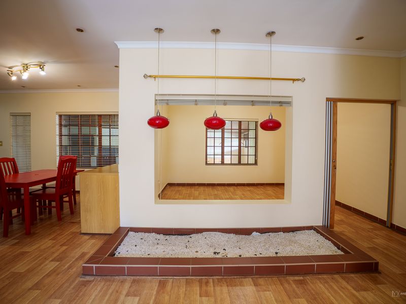 Open plan living area featuring laminate flooring, recessed lighting, and a unique internal feature planter box with decorative stone.