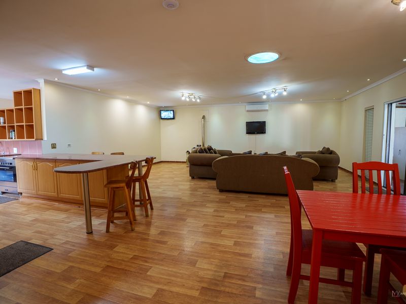 Spacious open-plan living area featuring a functional kitchen with built-in cabinetry, a breakfast bar, and laminate flooring throughout.