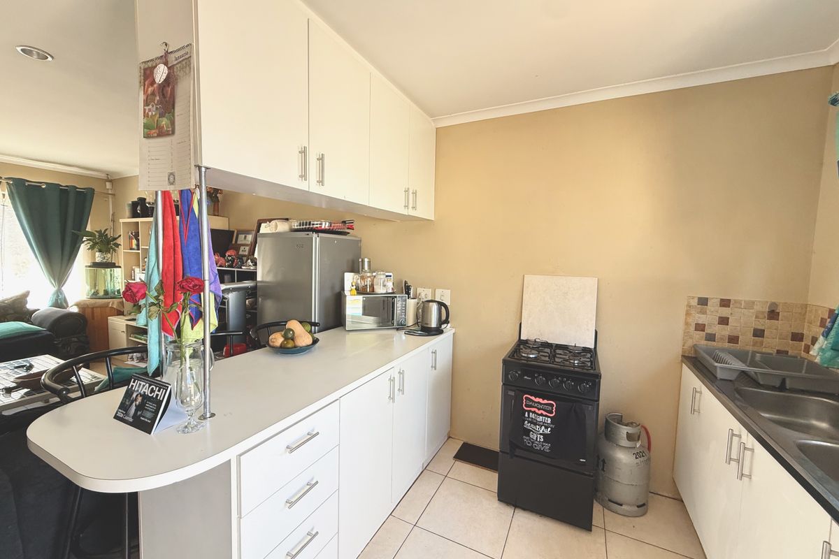 Functional kitchen featuring white cabinetry, gas stove, double bowl sink, and a breakfast bar, offering a practical layout for daily meal preparation.