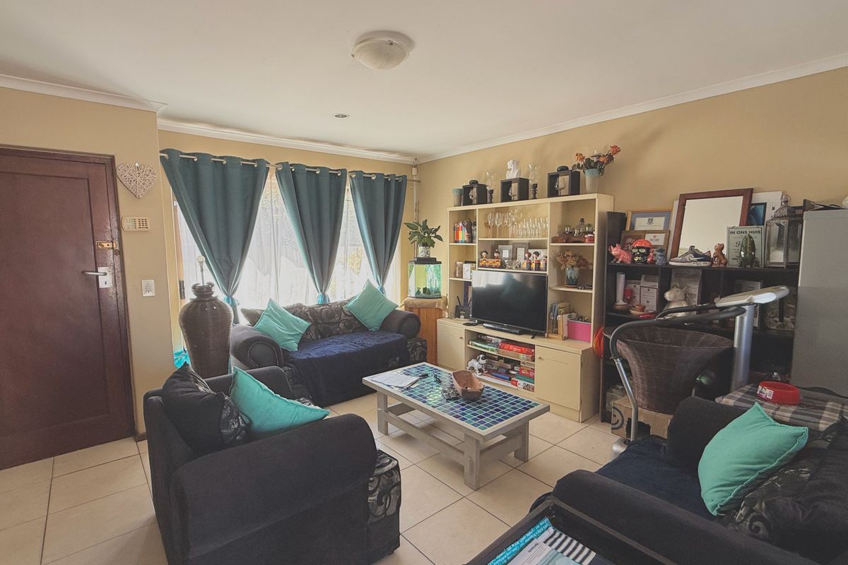 A living room featuring tiled flooring, recessed lighting, and a sliding glass door providing natural light.