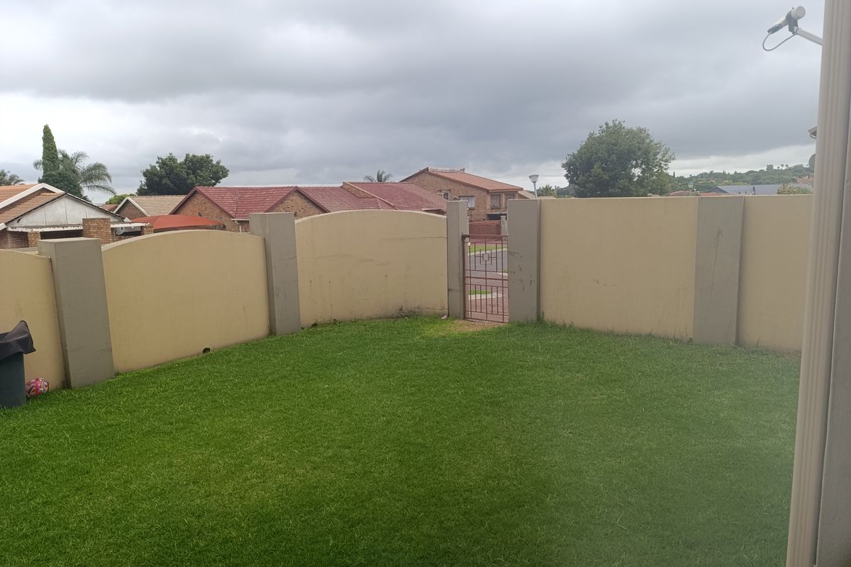 A private rear garden featuring a well-maintained lawn enclosed by solid boundary walls and a secure metal pedestrian gate.