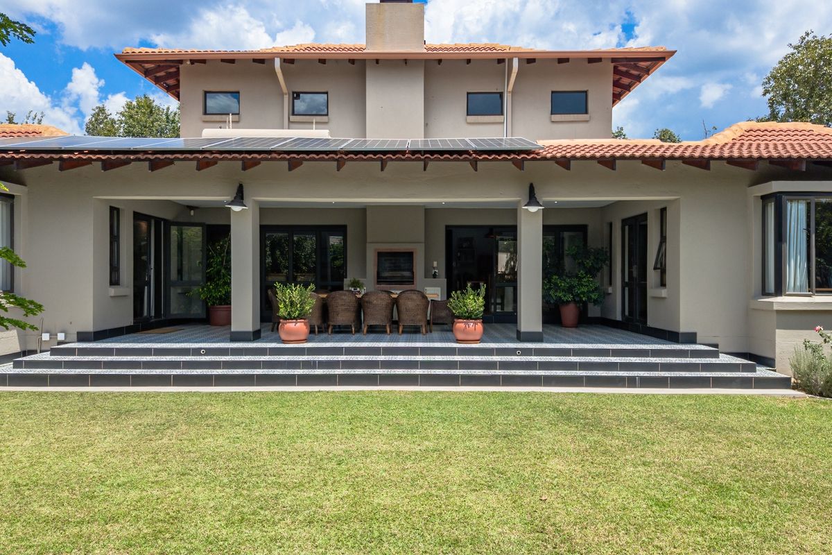 Spacious rear exterior featuring a covered patio with a built-in fireplace, tiled flooring, and solar panels installed on the roof.