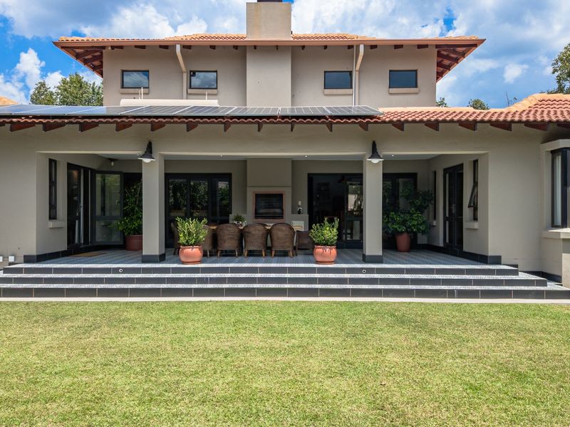 Spacious rear exterior featuring a covered patio with a built-in fireplace, tiled flooring, and solar panels installed on the roof.