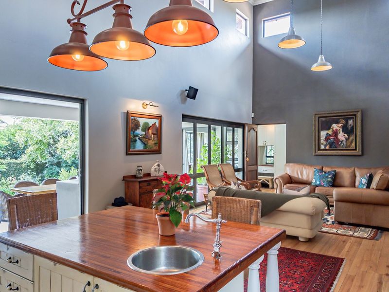 Spacious open-plan living area featuring high vaulted ceilings, hardwood flooring, and seamless access to the outdoor patio through large sliding glass doors.