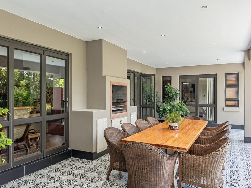Spacious covered patio featuring patterned floor tiles, recessed lighting, and a built-in braai, providing a seamless transition between indoor and outdoor living areas.
