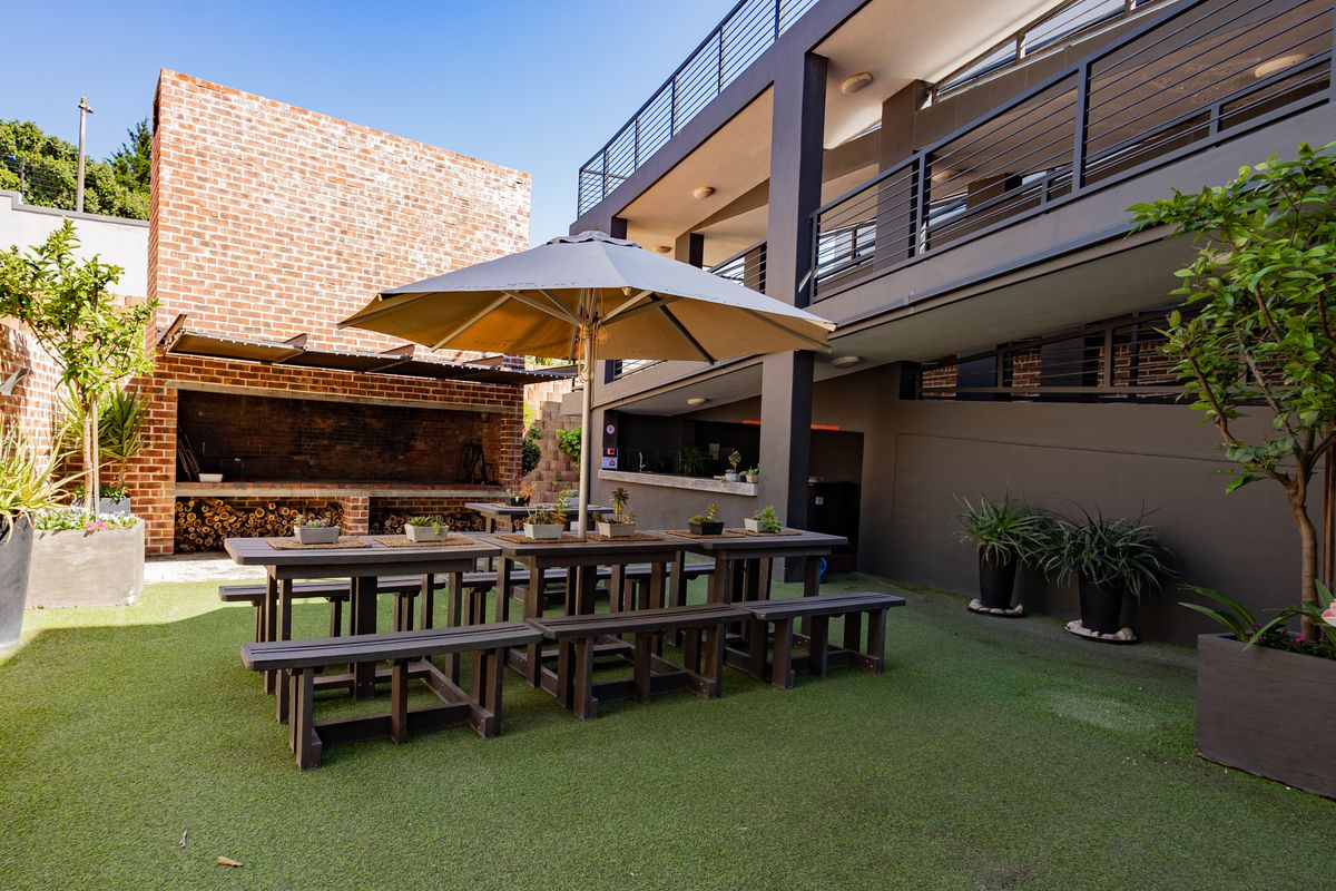 A well-maintained rear courtyard featuring a built-in brick braai, artificial lawn, and a covered outdoor entertainment area with a bar counter.