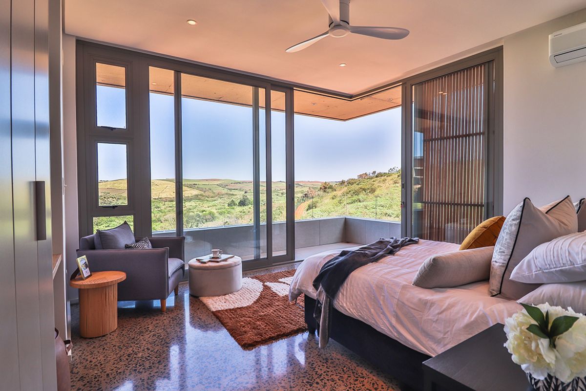 Modern bedroom featuring polished terrazzo floors, built-in cabinetry, a ceiling fan, and expansive sliding glass doors opening to a private balcony with scenic views.
