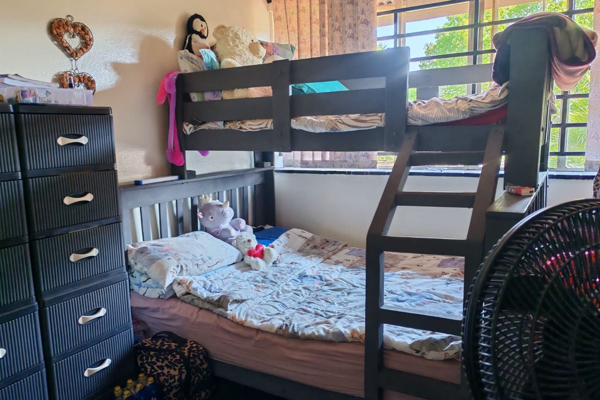 A bedroom featuring a window with security bars and standard interior finishes.