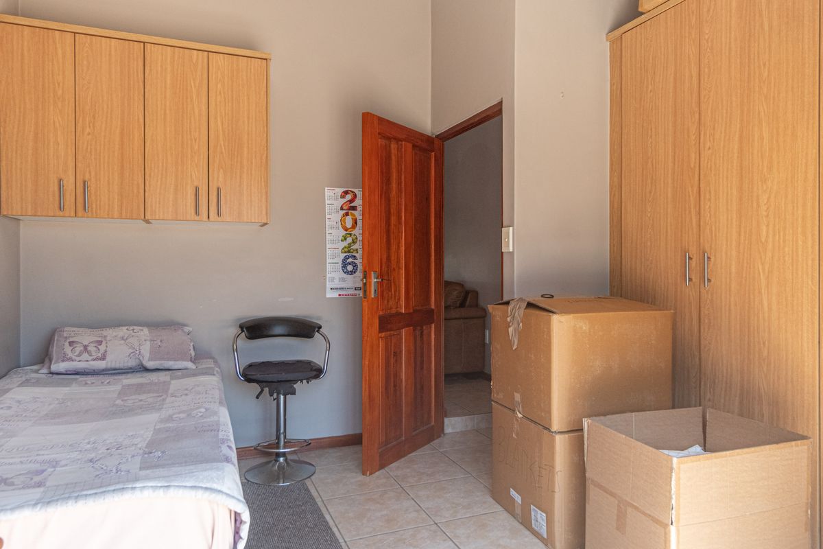 A bedroom featuring built-in wooden cabinetry, tiled flooring, and a solid timber door, providing functional storage and access to the adjacent living area.