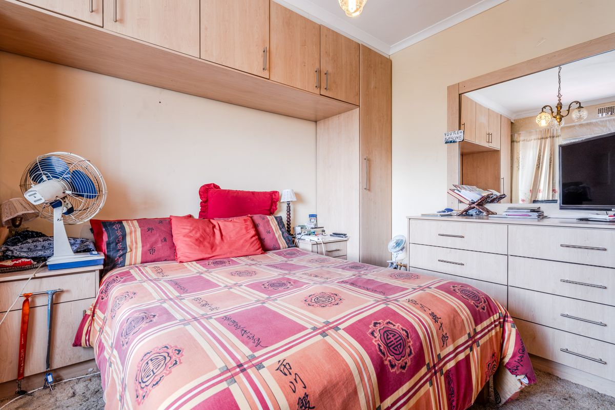 A bedroom featuring extensive built-in cabinetry, including overhead storage and a fitted mirror, providing ample storage space.