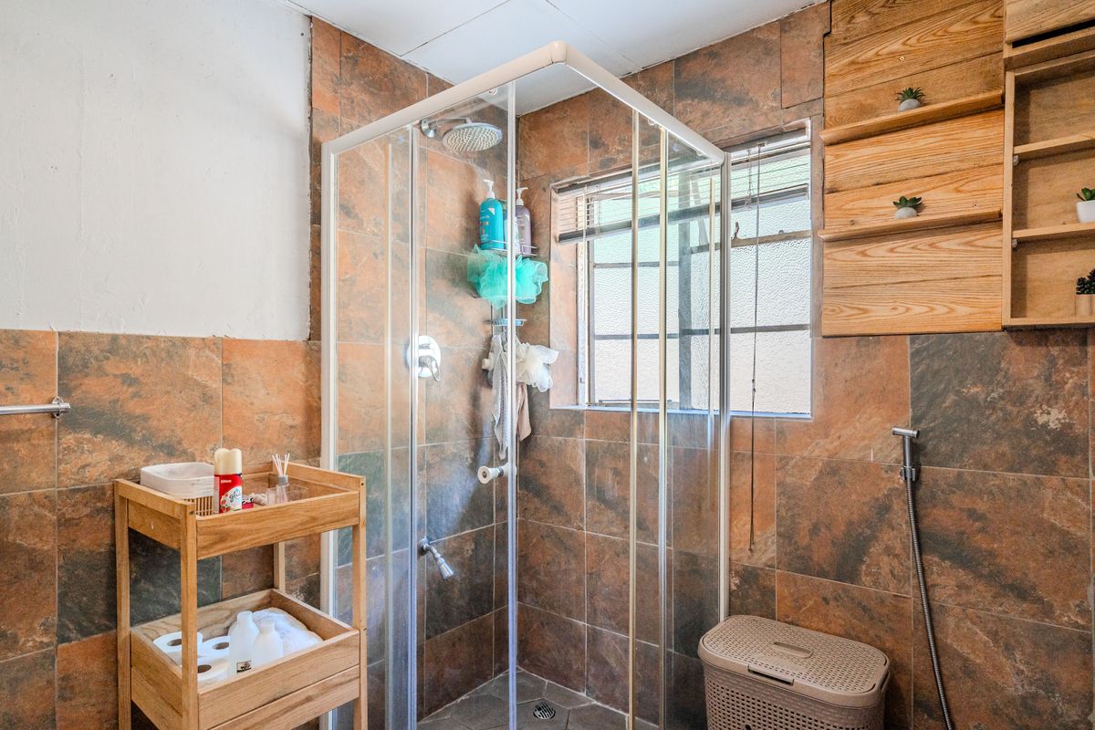 Bathroom featuring a shower enclosure with tiled walls and built-in shelving, requiring some finishing work on the upper wall sections.