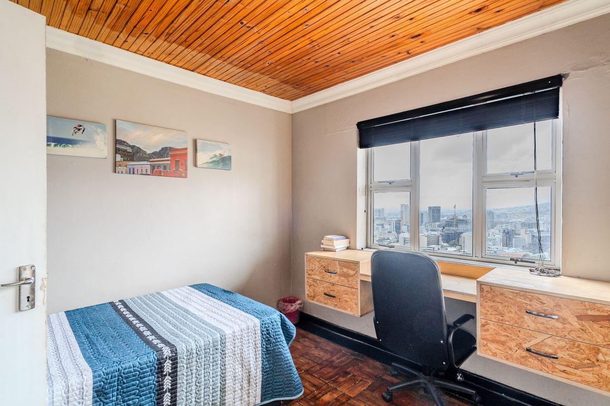 Bedroom featuring parquet flooring, a timber ceiling, and a built-in desk positioned under a window with city views.