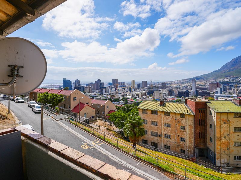 Elevated urban view overlooking the city skyline and surrounding residential apartment buildings from a balcony perspective.