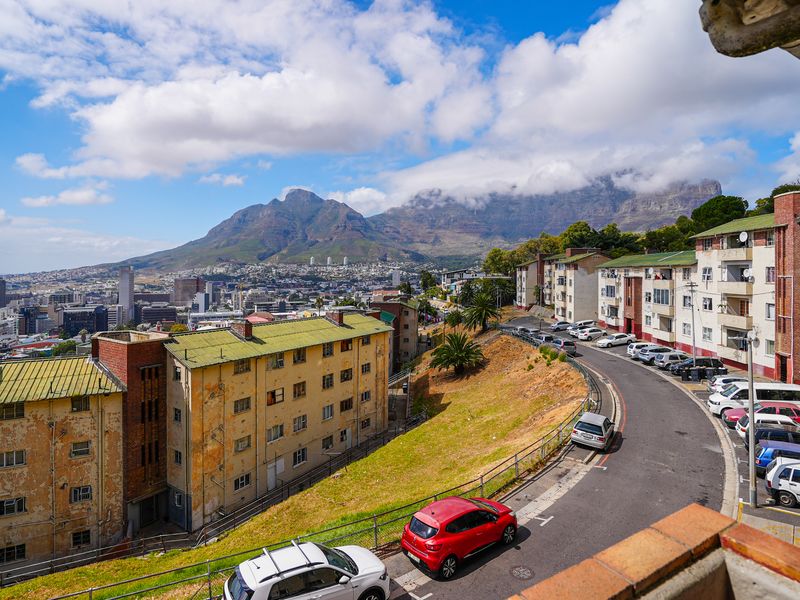 Elevated urban view overlooking residential apartment blocks, city skyline, and Table Mountain in the distance.