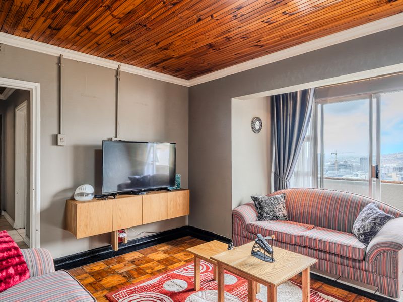 Living room featuring parquet flooring, a distinctive wooden ceiling, and sliding glass doors leading to a balcony with city views.
